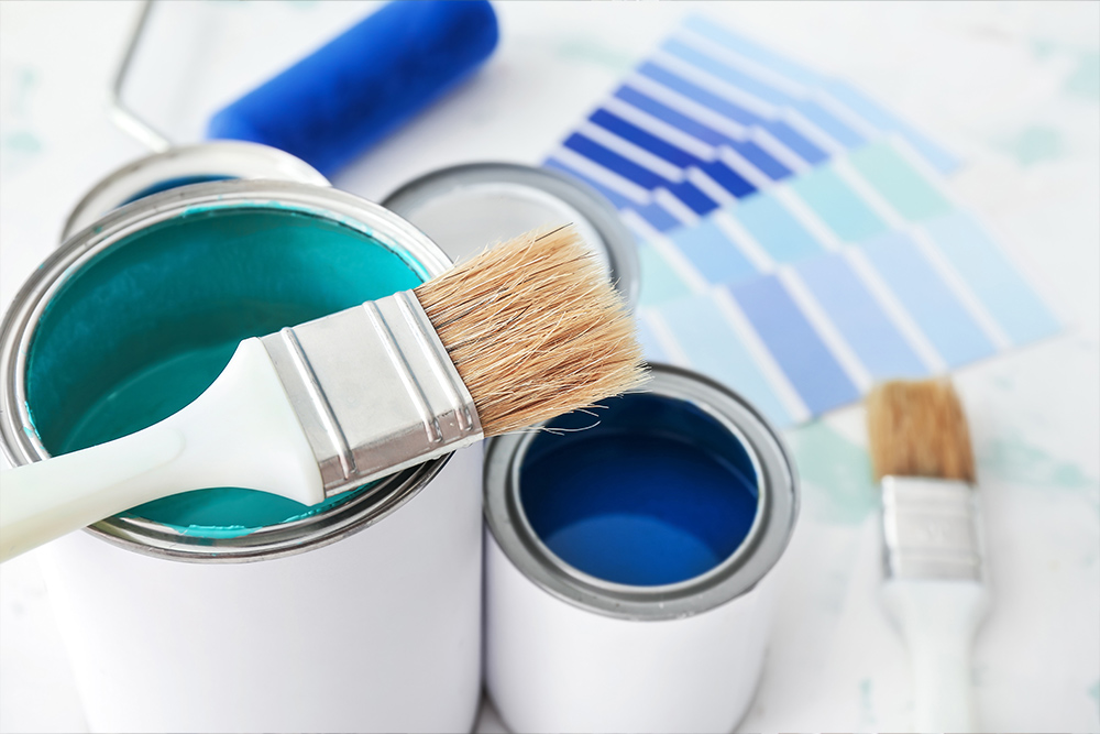 Cans of paint with brush on table, closeup